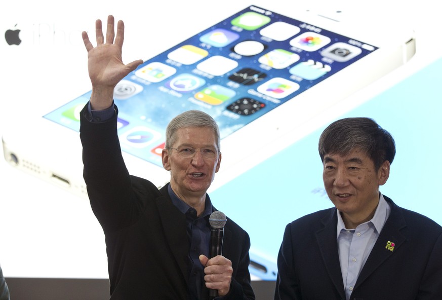 Apple&#039;s CEO Tim Cook, left, gestures as China Mobile&#039;s chairman Xi Guohua looks on during a promotional event that marks the opening day of sales of China Mobile&#039;s 4G iPhone 5s and iPho ...