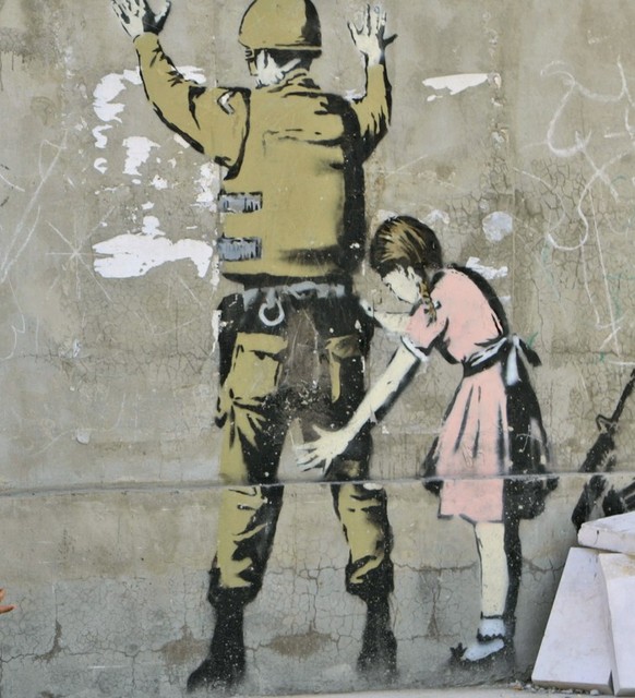 Palestinian youths are seen next to a wall painted by English graffiti artist Banksy in the West Bank city of Bethlehem, Wednesday, May 21, 2008. Bethlehem is hosting a three-day Palestinian business  ...