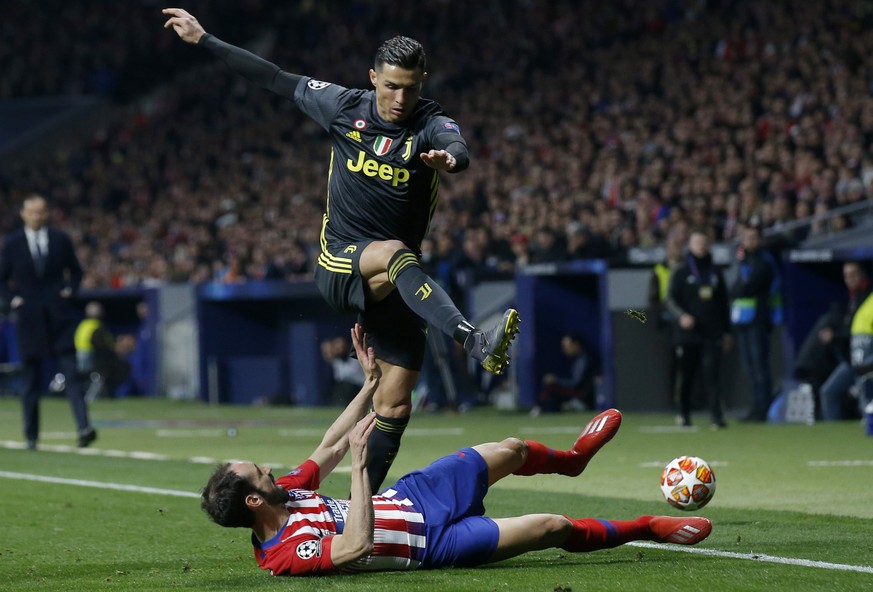 Juventus forward Cristiano Ronaldo jumps over Atletico defender Juanfran during the Champions League round of 16 first leg soccer match between Atletico Madrid and Juventus at Wanda Metropolitano stad ...