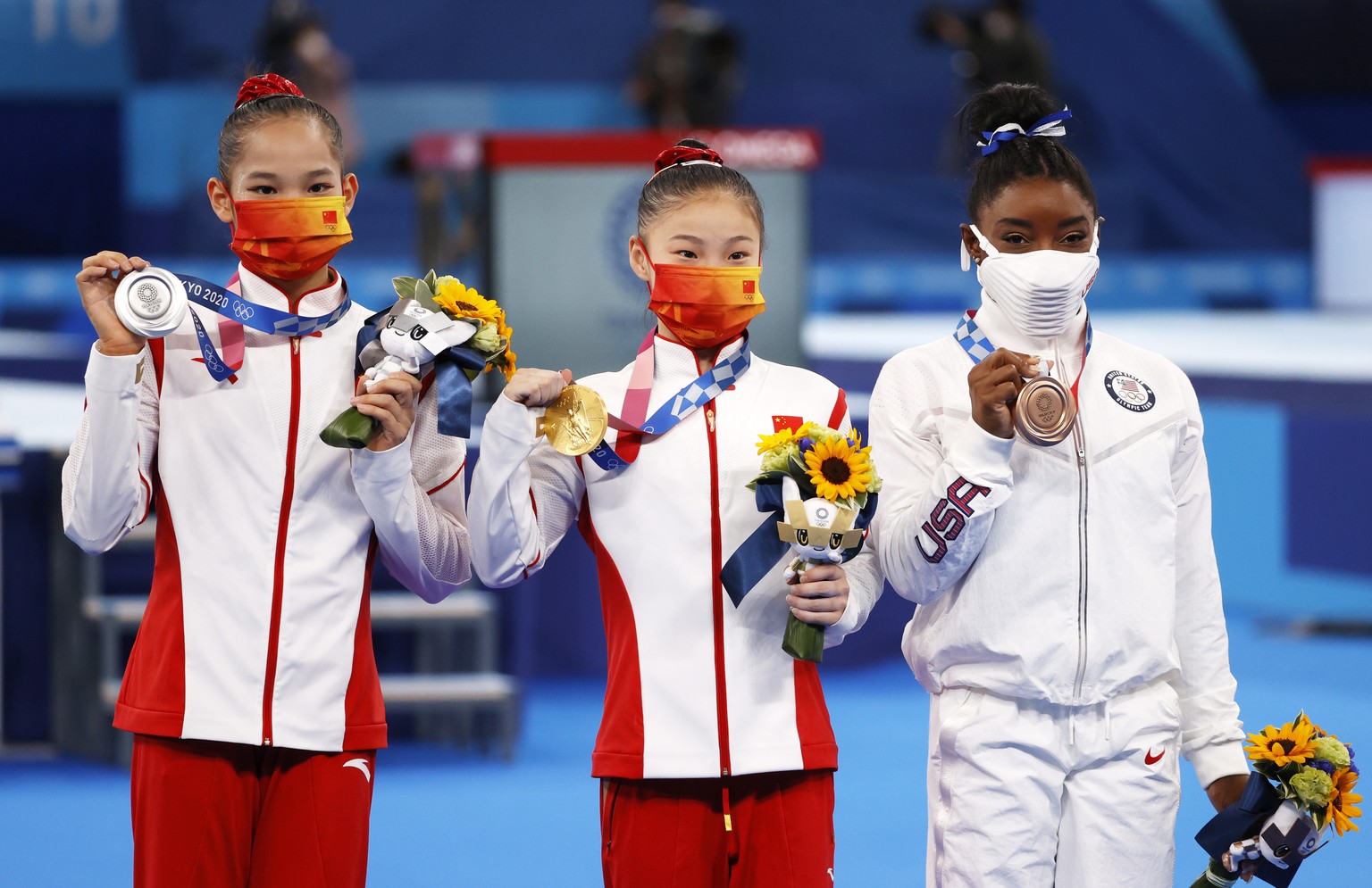 epa09390693 (L-R) - Silver medalist Tang Xijing of China, Gold medalist Guan Chenchen of China and Bronze medalist Simone Biles of USA pose on the podium after the Women&#039;s Balance Beam final duri ...