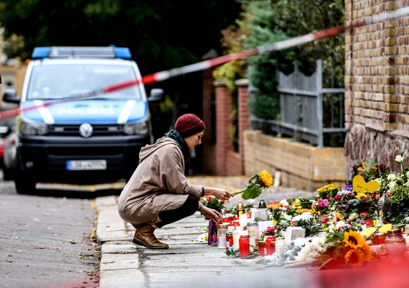 epa07912746 A woman places a flower in front of the synagogue in Halle Saale, Germany, 11 October 2019. According to the police two people were killed on 09 October in shootings in front of the synago ...