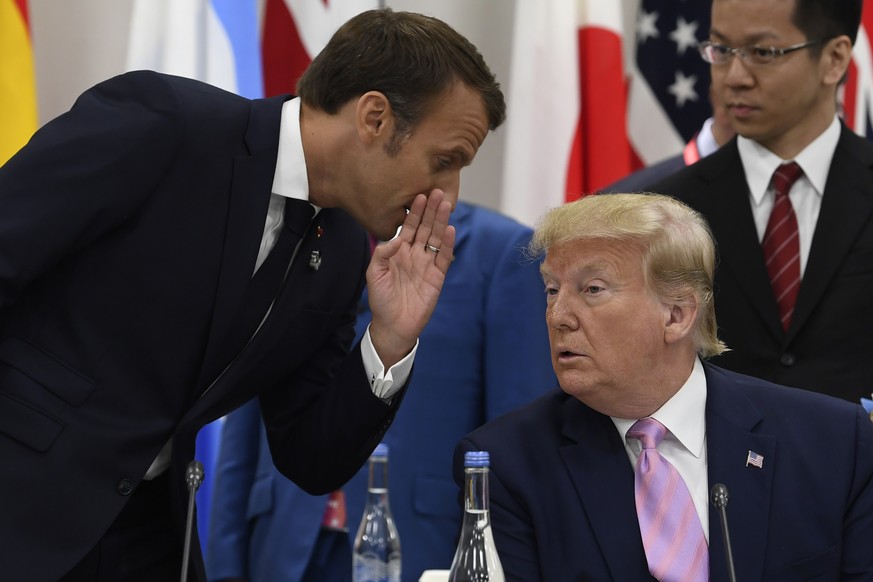 French President Emmanuel Macron, left, whispers to President Donald Trump, right, before the start of the G-20 summit event on the Digital Economy in Osaka, Japan, Friday, June 28, 2019. (AP Photo/Su ...