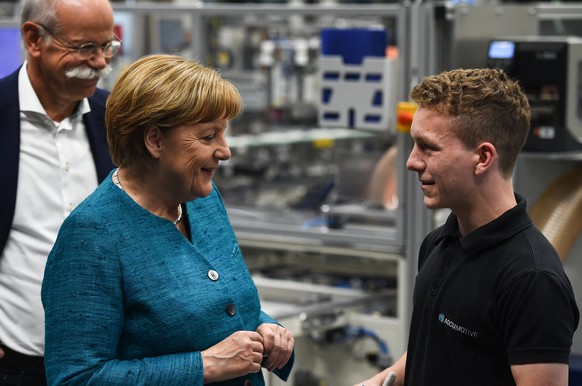 epa05981820 German Chancellor Angela Merkel (L) talks to a young worker (no name given) during a tour at the ACCUMOTIVE 1 car battery factory in Kamenz, Germany, 22 May 2017. Looking on is the chairma ...