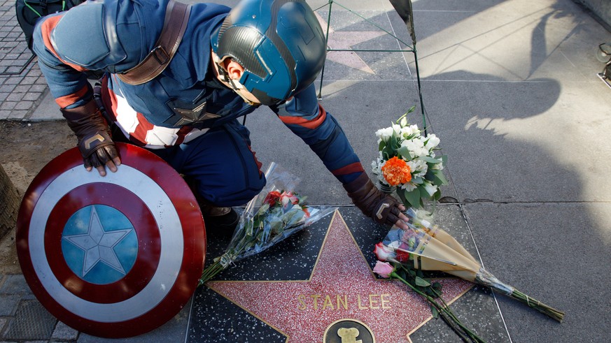 epa07161620 A Captain America impersonator touches the flowers covering the Walk of Fame star in memory of comic book wirter, publisher and editor Stan Lee, in Hollywood, California, USA, 12 November  ...