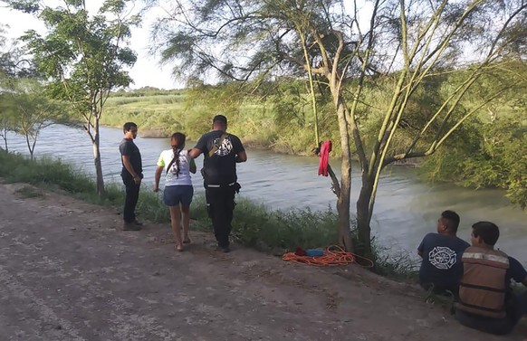 Tania Vanessa Ávalos of El Salvador, center left, is assisted by Mexican authorities after her husband and nearly two-year-old daughter were swept away by the current while trying to cross the Rio Gra ...