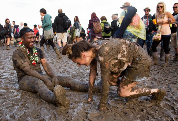 Festival goers react after falling over in the mud close to the Pyramid stage at Glastonbury music festival, England, Saturday, June 28, 2014. Thousands of music fans have arrived for the festival to  ...
