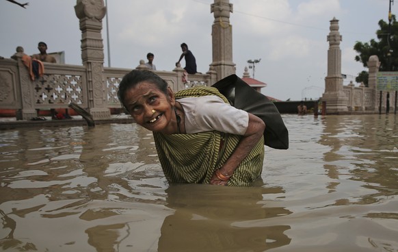 An elderly woman wades through waters of the swollen River Ganges in Varanasi, India, Saturday, Sept. 21, 2019. Heavy monsoon rains have raised the water level of the Ganges River above the danger lev ...