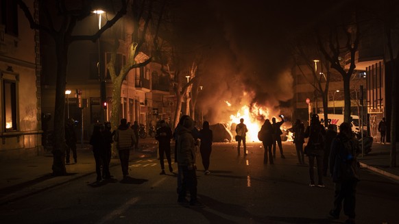 People gather near a burning barricade setup by demonstrators at the end of a protest condemning the arrest of rap singer Pablo Hasél in Barcelona, Spain, Saturday, Feb. 20, 2021. A fifth night of pea ...