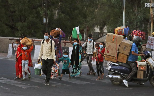A migrant worker family crosses a street as they leave city to go back to their villages during a nationwide lockdown to curb the spread of new coronavirus in New Delhi, India, Thursday, May 21, 2020. ...