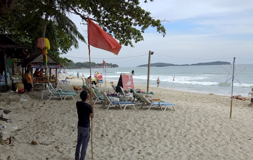 A man raises a red flag indicating rough weather conditions in Chaweng beach, Koh Samui, Thailand, Thursday, Jan. 3, 2019. Thai weather authorities are warning that a tropical storm will bring heavy r ...