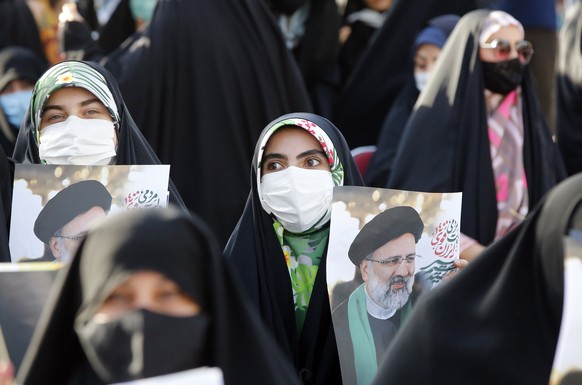 epa09277415 Women supporters of Iranian presidential candidate Ebrahim Raisi hold pictures depicting him, during an election campaign rally in Tehran, Iran, 16 June 2021. Iranians will vote in a presi ...
