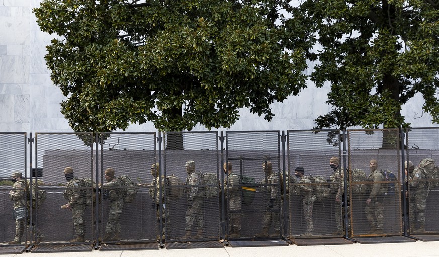 epaselect epa08942611 National Guard troops walking past the fence line around the US Capitol building in Washington, DC, USA, 16 January 2021. At least twenty thousand troops of the National Guard an ...