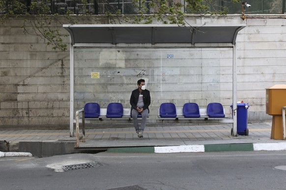 A man wearing a face mask to curb the spread of the new coronavirus sits at a bus stop, in Niavaran in northern Tehran, Iran, Thursday, April 16, 2020. Authorities have canceled ceremonies marking the ...