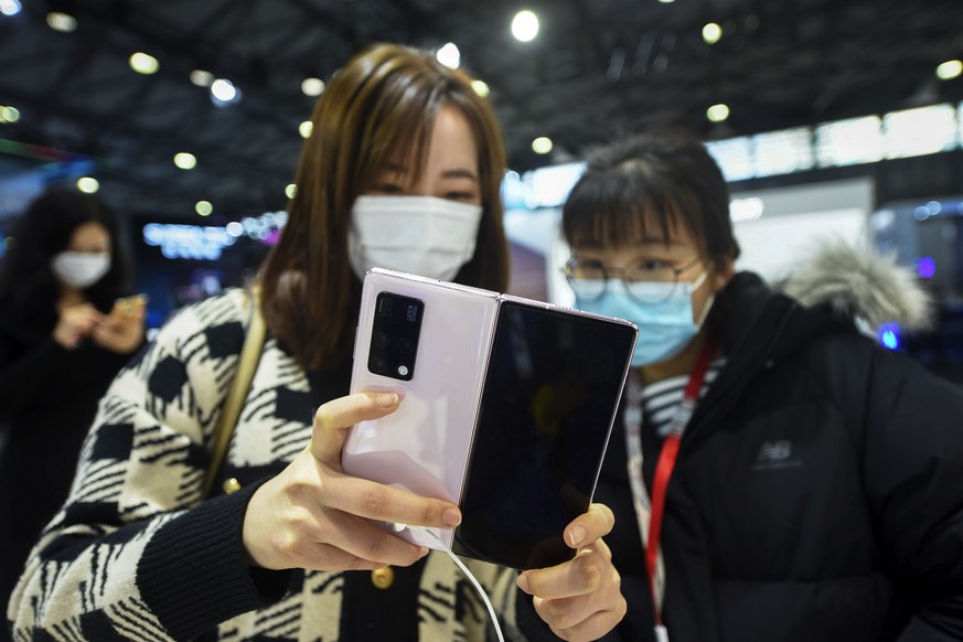 Women wearing face masks to help curb the spread of the coronavirus masks try out the Huawei&#039;s latest mobile phone Huawei Mate X2 at the Mobile World Congress in Shanghai, China on Tuesday, Feb.  ...