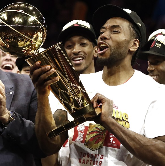 epa07647064 Toronto Raptors forward Kawhi Leonard (R) holds up the Larry O&#039;Brien NBA Championship Trophy after beating the Golden State Warriors in the NBA Finals game six at Oracle Arena, in Oak ...