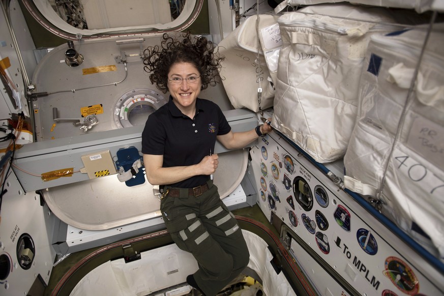 In this June 2019 photo made available by NASA, astronaut Christina Koch poses for a portrait inside of the vestibule between a SpaceX Dragon cargo craft and the Harmony module of the International Sp ...