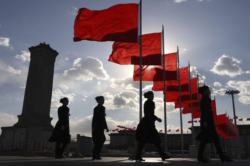 Bus ushers walk past red flags on Tiananmen Square during a plenary session of the Chinese People&#039;s Political Consultative Conference (CPPCC) at the Great Hall of the People in Beijing Monday, Ma ...