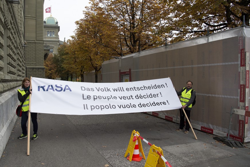 Zwie aktivisten halten ein Transparent mit der Aufschrift &quot;Das Volk will entscheiden!, Le peuple veut decider!, Il popolo vuole decidere!&quot;, waehrend Aktivistinnen- und Aktivisten im Namen de ...