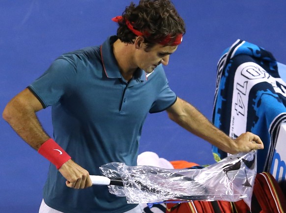 Federer zieht einen neuen Schläger aus der Plastikhülle, auf die Yu und Ferguson sein RF-Logo gedruckt haben.