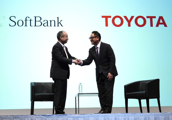 FILE - In this Oct. 4, 2018, file photo, Softbank Group Corp. Chairman Masayoshi Son, left, and Toyota Motor Corp. President Akio Toyoda shake hands after their talk as part of a joint press conferenc ...