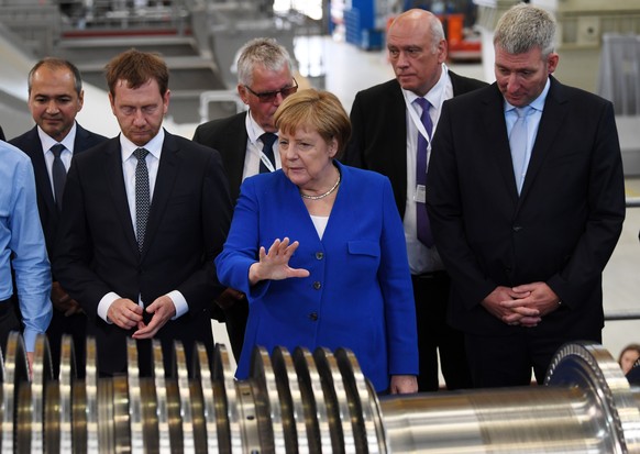 epa07718761 German Chancellor Angela Merkel (C) inspects a turbine next to the Prime Minister of Saxony, Michael Kretschmer (L) and the director of the Siemens turbine plant in Goerlitz, Ronald Schmid ...