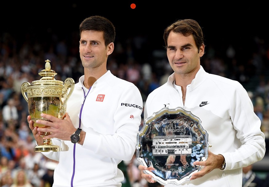 epa04844403 Novak Djokovic (L) of Serbia celebrates with the trophy after winning against Roger Federer (R) of Switzerland during their final match for the Wimbledon Championships at the All England L ...