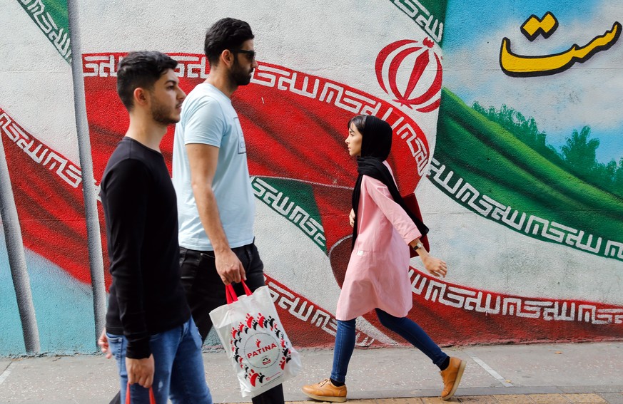 epa07554840 Iranians walk past a graffiti on a wall of the national flag, on the eve of the first anniversary of the US withdrawal from the Iran nuclear deal, in Tehran, Iran, 07 May 2019 (issued 08 M ...
