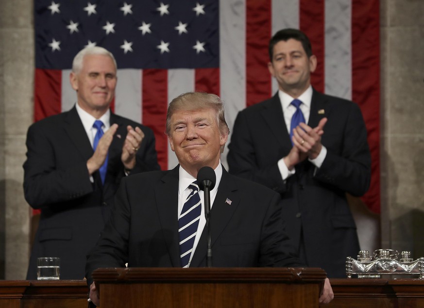 US Vice President Mike Pence (L) and Speaker of the House Paul Ryan (R) applaud as US President Donald J. Trump (C) arrives to deliver his first address to a joint session of Congress from the floor o ...