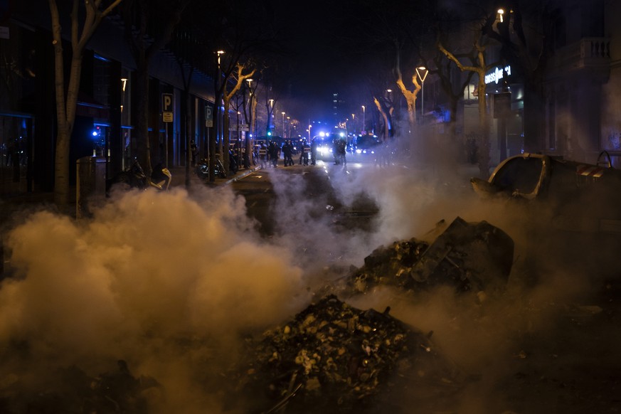 Police officers stand guard near a burning barricade setup by demonstrators at the end of a protest condemning the arrest of rap singer Pablo Hasél in Barcelona, Spain, Saturday, Feb. 20, 2021. A fift ...