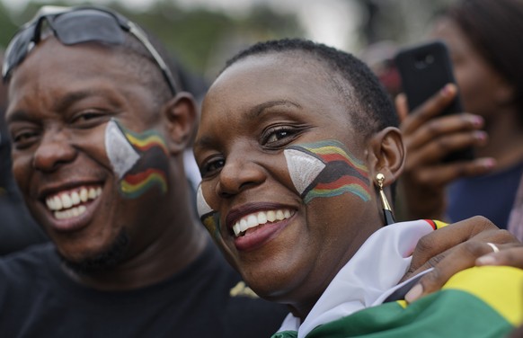 A couple wearing face paint of the national flag join tens of thousands demanding that President Robert Mugabe stand down at Zimbabwe Grounds in Harare, Zimbabwe Saturday, Nov. 18, 2017. In a euphoric ...