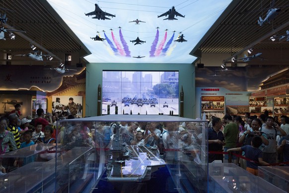 Visitors look at a scale model of a Chinese aircraft carrier during an exhibition to mark the 90th anniversary of the founding of the People&#039;s Liberation Army at the military museum in Beijing, C ...
