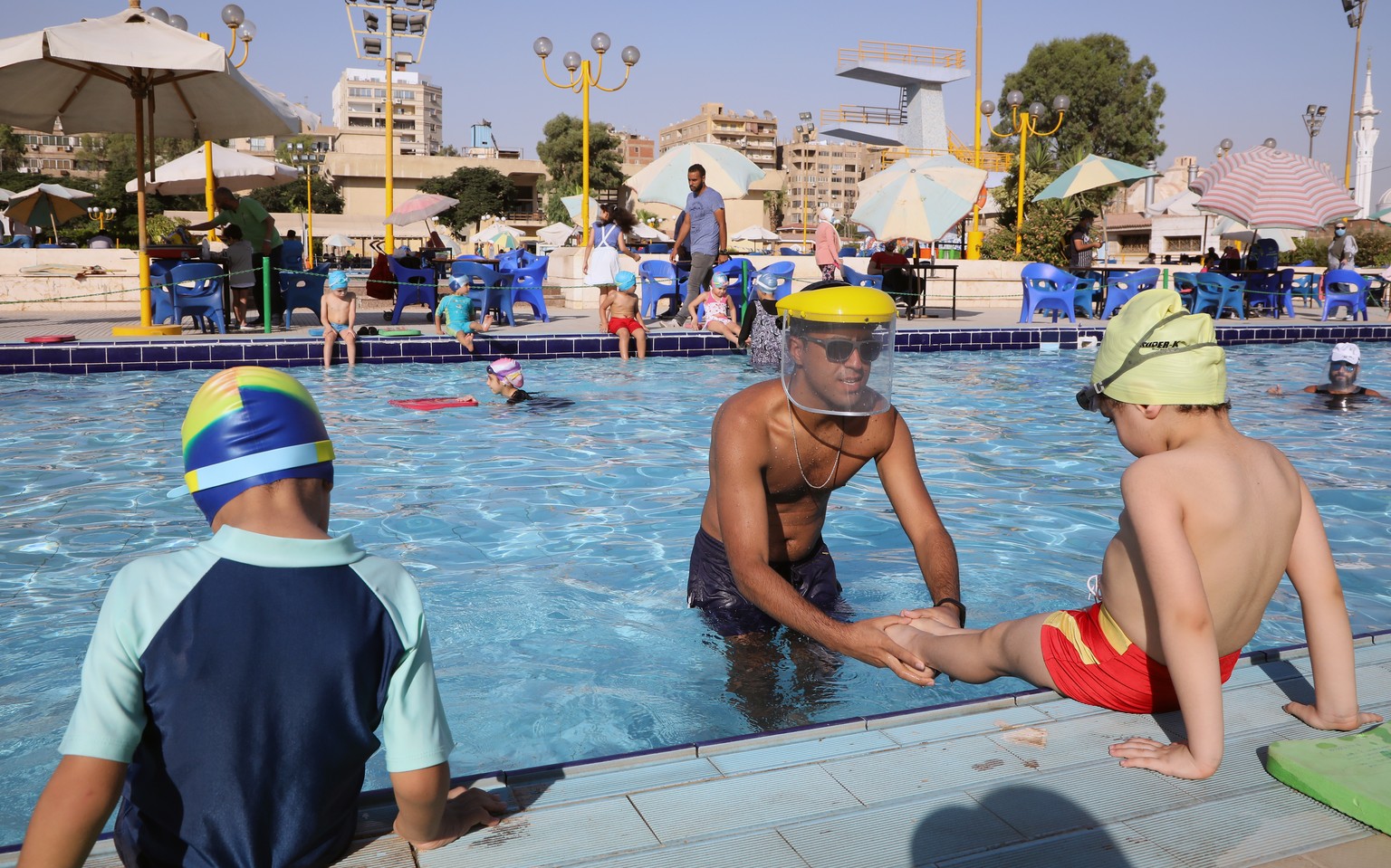 epa08540620 Coaches wear face sheilds during swimming classes at a sporting club in Cairo, Egypt, 11 July 2020. EPA/KHALED ELFIQI