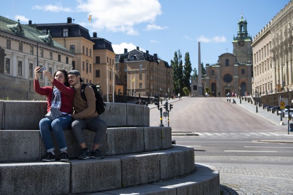 epa08560423 Two tourists take a selfie outside the Royal palace (R) in central Stockholm, Sweden, 22 July 2020. The usually tourist-packed streets in the old town are almost deserted due to the COVID- ...
