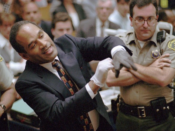 FILE - In this June 15, 1995 file photo, O.J. Simpson, left, grimaces in a Los Angeles courtroom, as he tries on one of the leather gloves prosecutors say he wore the night his ex-wife Nicole Brown Si ...