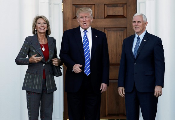 U.S. President-elect Donald Trump (C) and Vice President-elect Mike Pence stand with Betsy DeVos (L) before their meeting at the main clubhouse at Trump National Golf Club in Bedminster, New Jersey, U ...