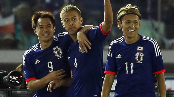 epa04793611 Japan&#039;s forward Keisuke Honda (C) celebrates with his teammates Shinji Okazaki (L) and Takashi Usami (R) after scoring the opening goal during the international friendly soccer match  ...