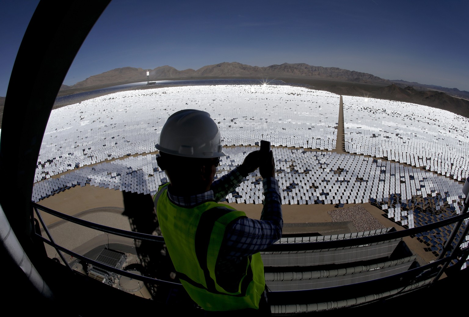 FILE - In this Feb. 11, 2014, file photo, made with an extreme wide-angle lens, Jeff Holland takes a picture of some of the 300,000 computer-controlled mirrors that reflect sunlight to boilers that si ...