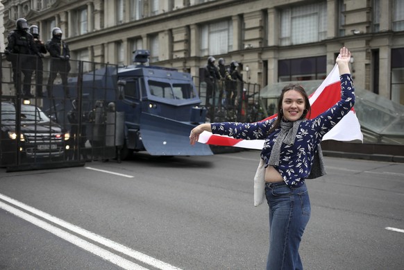A woman waves an old Belarusian national flag in front of police barricade blocked a street during an opposition rally to protest the official presidential election results in Minsk, Belarus, Sunday,  ...