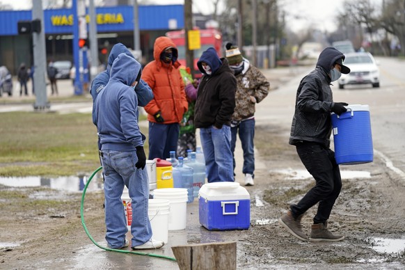 Juan Lopez, right, carries a cooler full of water after filling it with a hose from a park spigot Thursday, Feb. 18, 2021, in Houston. Houston and several surrounding cities are under a boil water not ...