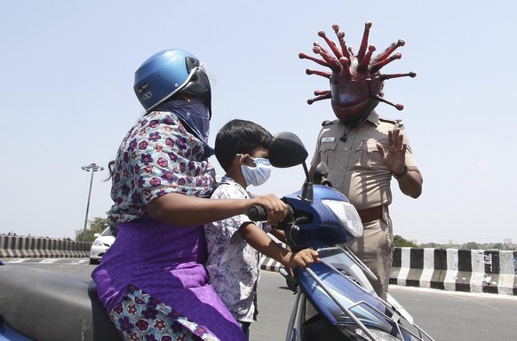 Police officer Rajesh Babu wears a helmet representing the coronavirus, and requests commuters to stay home during the 21-day countrywide lockdown that began Wednesday in Chennai, India, Saturday, Mar ...