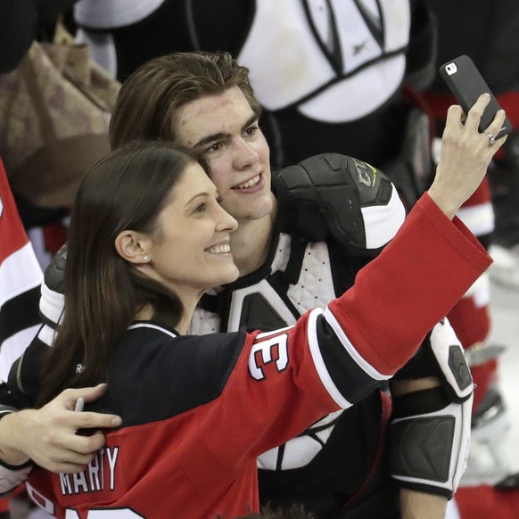 New Jersey Devils center Nico Hischier, right, of Switzerland, takes a photo with a fan after defeating the Toronto Maple Leafs in an NHL hockey game, Thursday, April 5, 2018, in Newark, N.J. (AP Phot ...