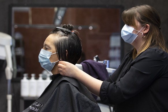 Eine Coiffeuse des Coiffeursalons Gallery Hairstyle schneidet einer Kundin die Haare, am Montag, 27. April 2020 in Bern. Coiffeure duerfen ihre Geschaefte ab heute wieder oeffnen. (KEYSTONE/Peter Klau ...