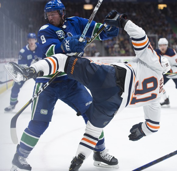 Vancouver Canucks center J.T. Miller (9) fights for control of the puck with Edmonton Oilers center Gaetan Haas (91) during the second period of an NHL hockey game Monday, Dec. 23, 2019, in Vancouver, ...