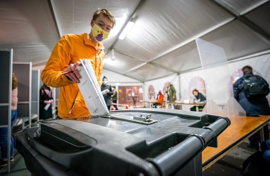 epa09079115 A voter casts an early vote for the House of Representatives elections in a temporary voting tent in front of Nijmegen station, in Nijmegen, The Netherlands, 17 March 2021. Special measure ...
