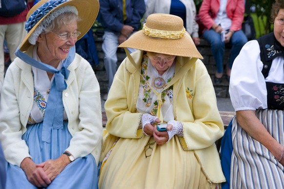 Eine aeltere Frau in einer Tracht schreibt ein SMS auf ihrem Handy am Unspunnenfest am 3. September 2006 in Interlaken. Das Unspunnenfest feiert das 200-jaehrige Jubilaeum. (KEYSTONE/Martin Ruetschi)  ...