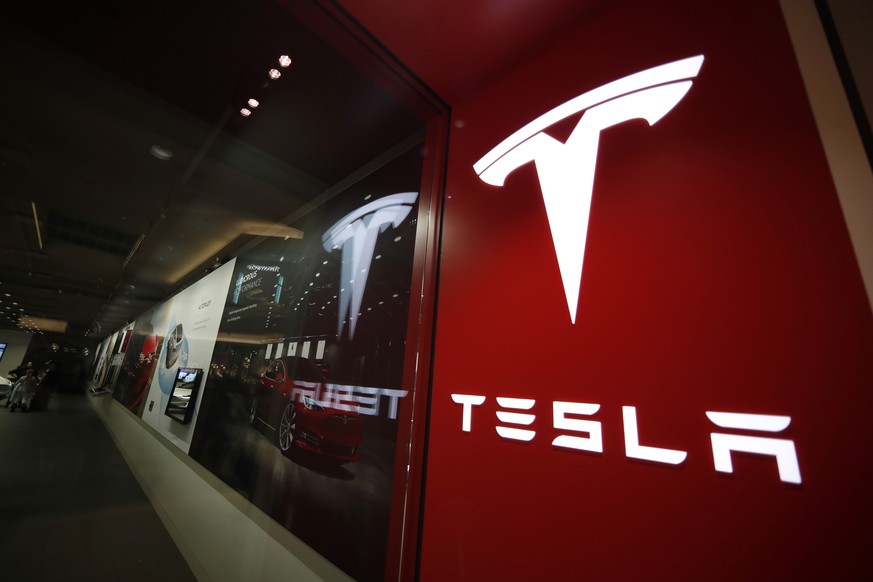 FILE- In this Feb. 9, 2019, file photo, a sign bearing the company logo is displayed outside a Tesla store in Cherry Creek Mall in Denver. Tesla is walking back its plan to close most retail stores wo ...