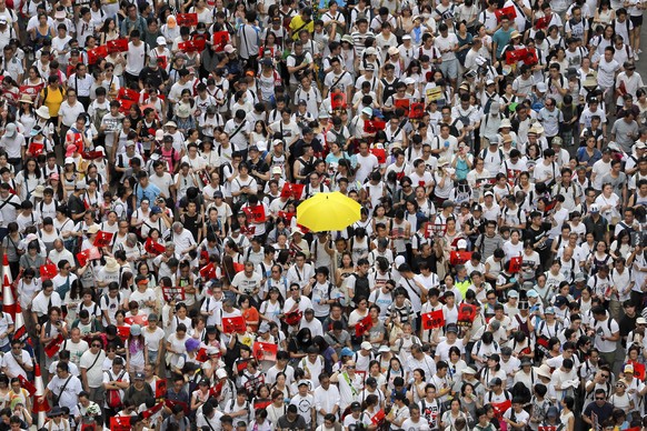 In this Sunday, June 9, 2019, file photo, a protester holds up a yellow umbrella as he and others march in a rally against the proposed amendments to extradition law in Hong Kong. A sea of protesters  ...