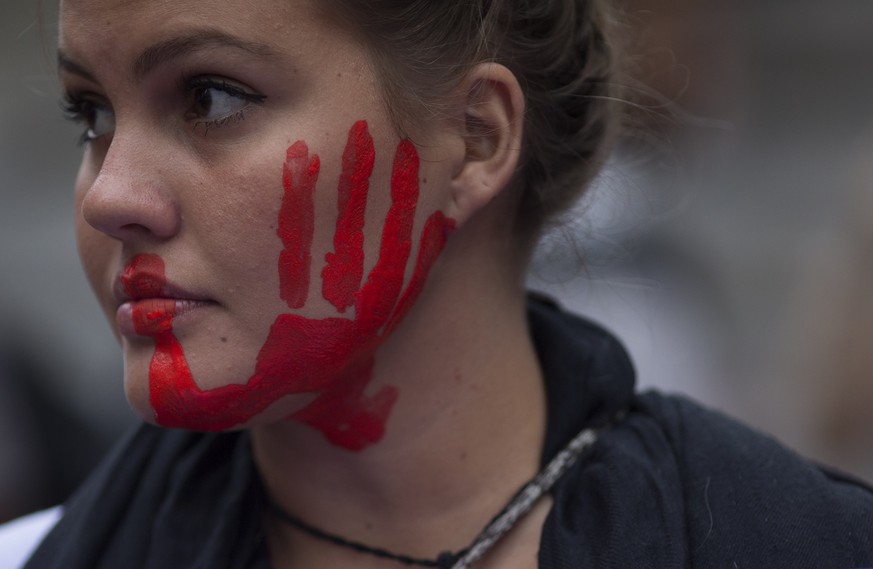 A woman with a red hand painted on her face participates in a demonstration against gender violence in Rio de Janeiro, Brazil, Tuesday, Oct. 25, 2016. Women in Brazil organized protests condemning vio ...