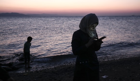 A migrant checks a mobile device after crossing with a dinghy from Turkey to the southeastern Greek island of Kos, Wednesday, Aug. 12, 2015. Dozens of boat people from the Middle East are flowing into ...