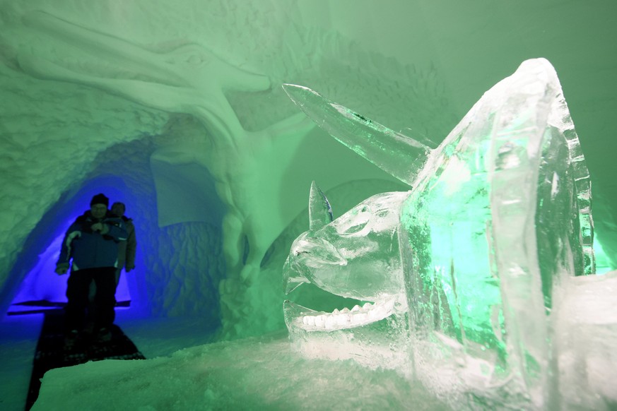 epa06403902 Visitors look at ice sculptures of dinosaurs and other prehistoric animals on display in an artificial cave measuring more than 30 metres long and 15 metres wide and made with 1,200 m3 of  ...
